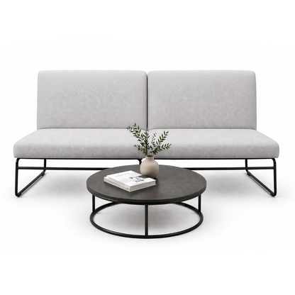 Gray sofa with a round coffee table featuring a vase and books on a white background