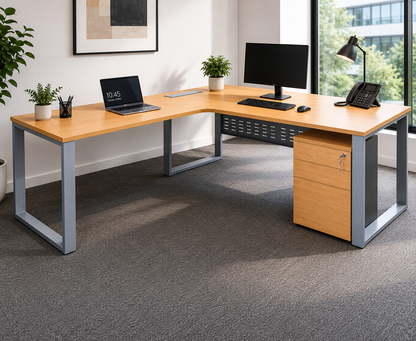 Modern office desk with computer setup in a bright room with large windows.