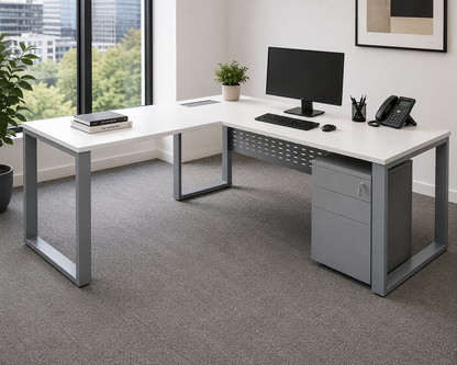 Modern office desk with computer setup in a bright room with large windows.